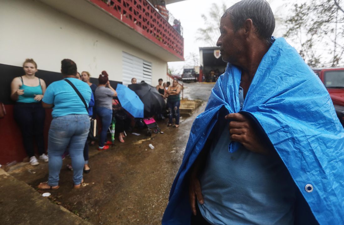 : Arian Rodriguez covers himself with a tarp as residents wait in the rain to register with FEMA more than two weeks after Hurricane Maria hit the island, on October 9, 2017 in Jayuya, Puerto Rico. <br/>